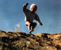 Farbfoto: ein im Sand springendes Kind