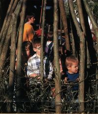 Farbfoto: Kinder in einem Zelt aus Weidenästen